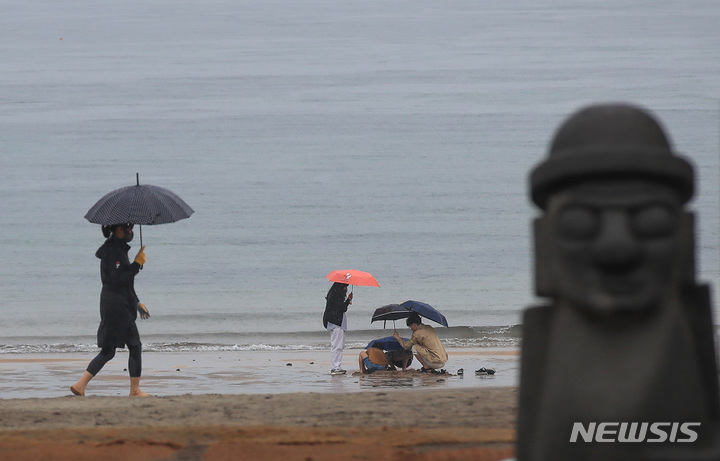 [제주=뉴시스] 우장호 기자 = 비가 내리기 시작한 지난 3일 오후 제주시 이호해변에 우산을 쓴 관광객들이 지나가고 있다. 2023.05.03. woo1223@newsis.com