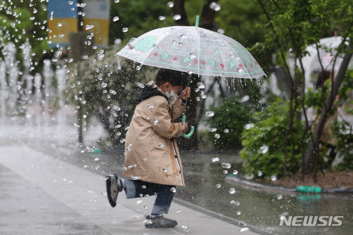 [서울=뉴시스] 권창회 기자 = 지난 5일 오전 서울 종로구 광화문광장에서 어린이가 우산을 쓰고 분수대 사이를 지나가고 있다.2023.05.05. kch0523@newsis.com