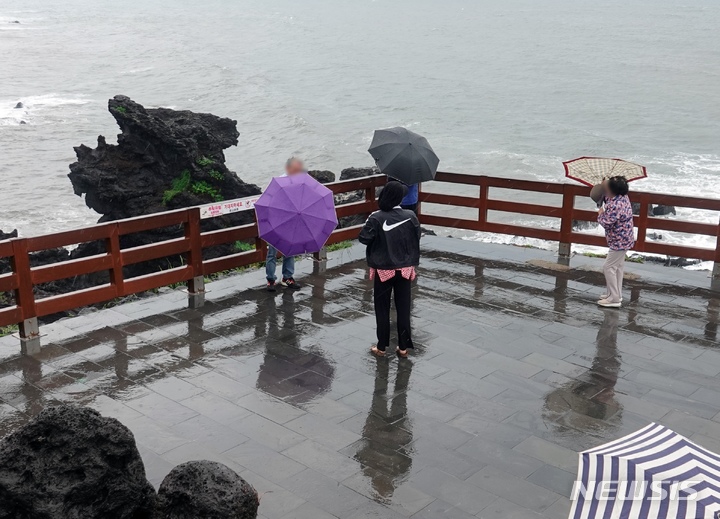 [제주=뉴시스] 오영재 기자 = 강한 비바람이 치고 있는 지난달 7일 오전 제주시 용두암에서 관광객들이 우산을 잡고 있다. 2023.05.07. oyj4343@newsis.com