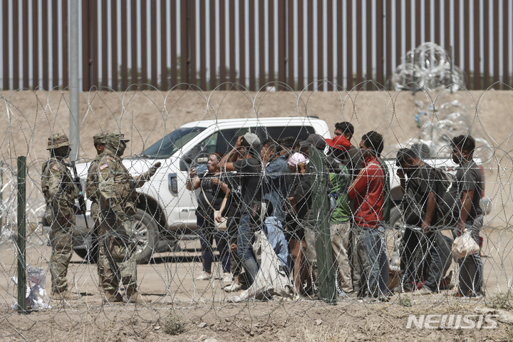 [엘패소=AP/뉴시스]미국 연방대법원이 허가없이 입국한 이민자를 체포할 수 있도록 허용한 텍사스주 새 이민법에 대한 효력정지 명령을 19일(현지시각) 해제했다. 사진은 지난해 5월11일 멕시코 시우다드 후아레스에서 철조망을 넘어 미 텍사스주 엘패소로 들어온 이민자들이 텍사스주 방위군의 지시사항을 듣고 있는 모습. 2024.03.20.