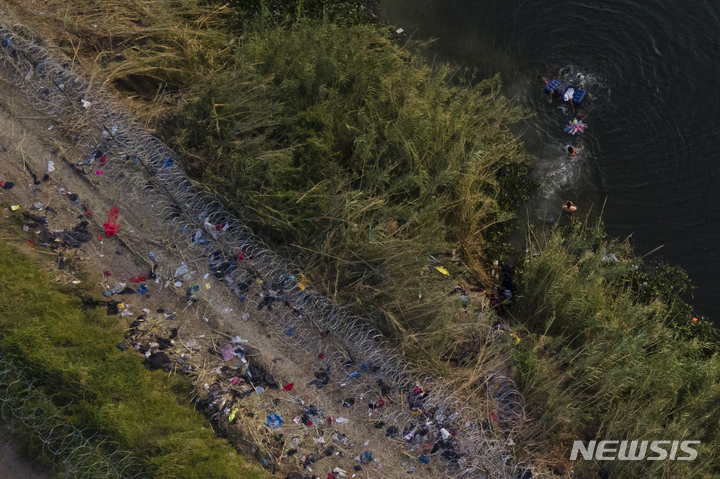 [텍사스=AP/뉴시스] 11일(현지시간) 미국-멕시코 국경 인근 리오그란데강에서 이민자들이 미국 영토로 들어가기 위해 강을 건너고 있다. 2023.05.12.