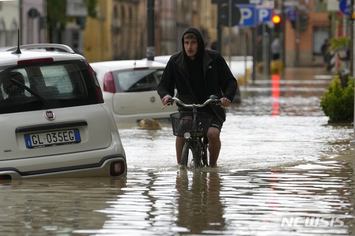 [카스텔 볼로네제=AP/뉴시스] 17일(현지시각) 이탈리아 에밀리아-로마냐주 카스텔 볼로네제 마을에서 자전거를 탄 사람이 침수 거리를 힘겹게 헤쳐 나가고 있다. 가뭄이 이어지던 이탈리아 북부에 폭우가 내리면서 홍수가 발생, 최소 8명이 숨지고 주민 수천 명이 대피했다. 2023.05.18.
