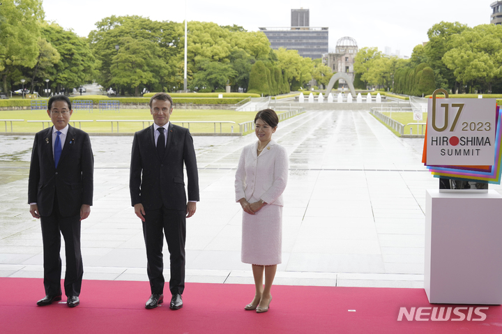 [히로시마=AP/뉴시스]19일 주요 7개국(G7) 정상회의가 일본 히로시마에서 개막했다. 기시다 후미오 일본 총리 부부가 히로시마 평화기념공원에서 에마뉘엘 마크롱 프랑스 대통령을 맞이해 함께 기념 촬영을 하고 있다. 왼쪽부터 기시다 총리, 마크롱 대통령, 기시다 유코 여사. 2023.05.19.