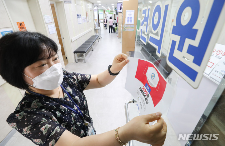 [서울=뉴시스] 황준선 기자 = 지난해 6월 1일 오후 서울 광진구 인구보건복지협회 서울지회 가족보건의원에서 관계자가 마스크 착용 의무 안내문을 제거하고 있다. 이날부터 코로나19의 위기경보 수준이 '심각'에서 '경계' 수준으로 하향 조정되며 마스크 착용 의무가 남아있던 의원급 의료기관과 약국에서도 '자율 착용'으로 전환됐다. (해당 사진은 기사와 직접 관련이 없습니다.) 2023.06.01. hwang@newsis.com