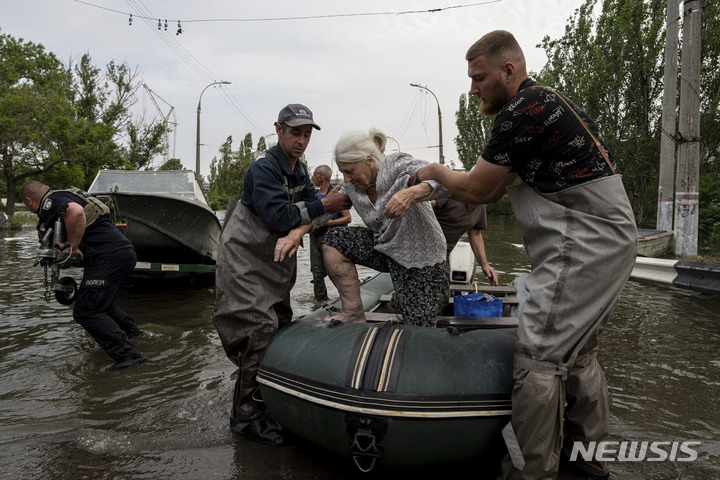 [헤르손=AP/뉴시스] 7일(현지시각) 우크라이나 헤르손 홍수 지역에서 구조대가 한 노인을 구조해 대피시키고 있다. 볼로디미르 젤렌스키 대통령은 "댐의 파괴로 수십만 명에 대한 식수 공급에 차질을 빚고 있다"라며 "주민 대피와 함께 긴급 식수 공급이 최우선 과제"라고 밝혔다. 2023.06.08.