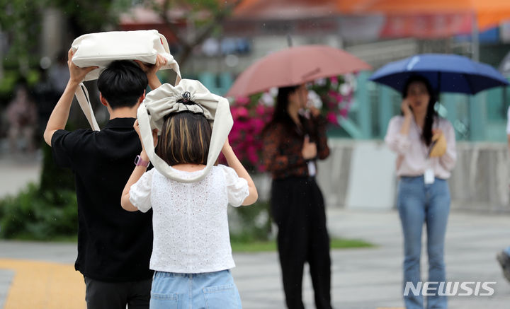 [서울=뉴시스] 김명년 기자 = 절기상 낮의 길이가 가장 길다는 하지(夏至)인 21일 수요일은 전국에 비가 내리다가 오후에 대부분 그치겠다. 사진은 지난 20일 오후 서울 광화문 사거리에서 시민들이 가방으로 머리를 가린 채 횡단보도를 건너고 있는 모습. 2023.06.20. kmn@newsis.com