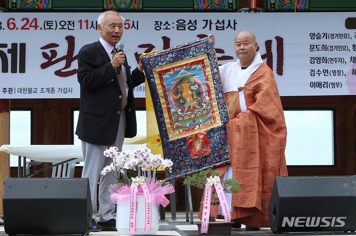 [음성=뉴시스] 강신욱 기자 = 24일 충북 음성군 음성읍 가섭사에서 열린 2023 음성 국제 판소리 축제에서 가섭사와 부탄왕국이 국제문화예술 자매결연을 하면서 김한영 주한부탄왕국명예총영사관이 부탄왕국이 선물한 탱화를 가섭사 주지 석상인 스님에게 전달하고 있다. 2023.06.24. ksw64@newsis.com