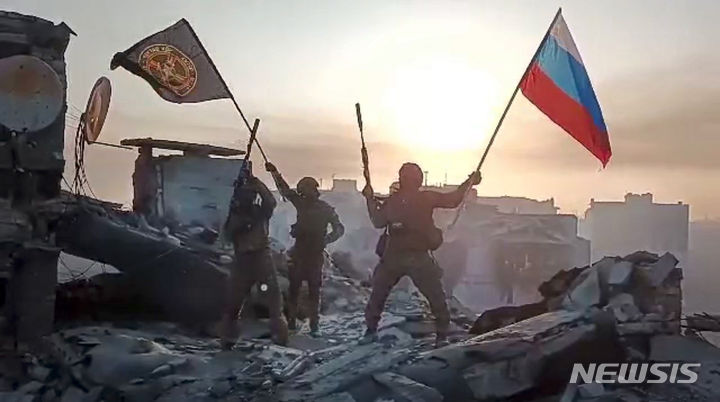 [바흐무트=AP/뉴시스]러시아 민간 용병회사 바그너가 우크라이나 바흐무트의 손상된 건물 위에서 러시아와 바그너 국기를 흔들고 있는 모습 202309.28.
