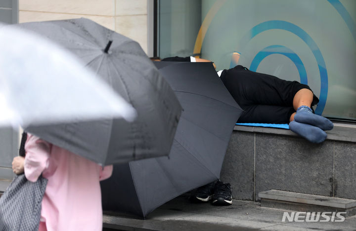 [서울=뉴시스] 김명년 기자 = 지난 7월13일 오후 서울 중구 명동거리에서 한 노숙자가 우산으로 비를 피한 채 누워있는 모습. 2023.07.13. kmn@newsis.com