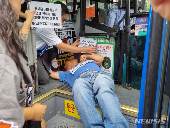 [서울=뉴시스] 김진엽 기자 = 전국장애인차별철폐연대(전장연)가 17일 오후 1시께 서울 종로구 혜화동로터리 앞 버스전용차로에서 시내버스 탑승 요구 시위를 진행하고 있다. 2023.07.17. wlsduq123@newsis.com