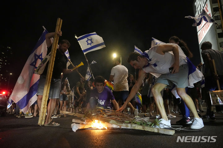 [텔아비브=AP/뉴시스] 18일(현지시각) 이스라엘 텔아비브에서 베냐민 네타냐후 총리의 사법 개편에 반대하는 시위대가 도로에 불을 피우고 있다. 이스라엘 전역에서 사법 개편에 반대하는 시위가 재개돼 수만 명의 시위대가 주요 도로 곳곳을 점거했다. 재계 관계자들은 사법 개편이 외국인 투자자들을 막을 것이라고 경고했고, 일부 공군 예비역들은 복무 거부를 선언했다. 2023.07.19.