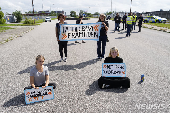 [말뫼=AP/뉴시스] 스웨덴 기후 운동가 그레타 툰베리(왼쪽)가 다른 운동가들과 함께 24일(현지시각) 스웨덴 말뫼의 석유 시설 입구 도로에서 시위하고 있다. 툰베리는 지난달 같은 곳에서 시위를 벌이던 중 교통에 방해가 된다는 이유로 장소를 옮기라는 경찰의 지시를 따르지 않은 '경찰 불복종' 혐의로 벌금형(약 30만 원)을 선고받은 지 불과 몇 시간 만에 다시 시위를 벌였다. 2023.07.25.