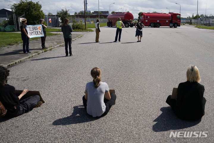 [말뫼=AP/뉴시스] 스웨덴 기후 운동가 그레타 툰베리(가운데)가 다른 운동가들과 함께 24일(현지시각) 스웨덴 말뫼의 석유 시설 입구 도로를 막고 시위를 벌이자 트럭 한 대가 되돌아가고 있다. 툰베리는 지난달 같은 곳에서 시위를 벌이던 중 교통에 방해가 된다는 이유로 장소를 옮기라는 경찰의 지시를 따르지 않은 '경찰 불복종' 혐의로 벌금형(약 30만 원)을 선고받은 지 불과 몇 시간 만에 다시 시위를 벌였다. 2023.07.25.