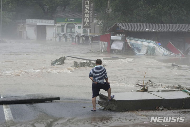 [베이징=AP/뉴시스] 1일(현지시간) 중국 베이징 샤오펑산에서 주민이 홍수로 침수된 지역을 바라보고 있다. 제5호 태풍 독수리가 중국 베이징에 상륙해 기록적인 폭우가 쏟아지면서 홍수가 발생했다. 2023.08.02.