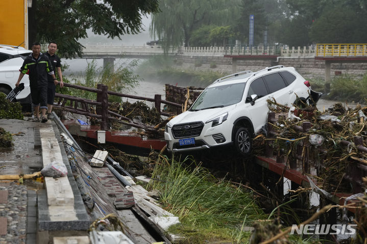 [베이징=AP/뉴시스] 1일(현지시간) 중국 베이징 먼터우거우구에서 주민들이 홍수로 떠내려온 차량 근처를 걷고 있다. 제5호 태풍 독수리가 중국 베이징에 상륙해 기록적인 폭우가 쏟아지면서 홍수가 발생했다. 2023.08.02.