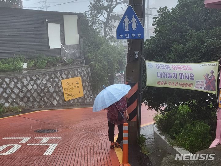 [부산=뉴시스] 김민지 기자 = 10일 제6호 태풍 카눈 북상으로 인해 불어오는 강한 비바람을 뚫고 부산 서구의 한 길가를 걸어 오르고 있는 노인의 모습. 2023.08.10. mingya@newsis.com