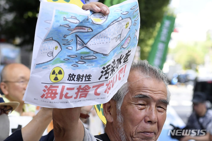 [도쿄=AP/뉴시스] 24일 일본 도쿄의 도쿄전력 본사 앞에서 시위대가 "오염수 해양 방류 반대"라고 쓰인 팻말을 들고 시위하고 있다. 일본 정부와 도쿄전력은 24일 오후 1시부터 후쿠시마 제1원자력발전소 오염수의 해양 방류를 시작한다. 2023.08.24.