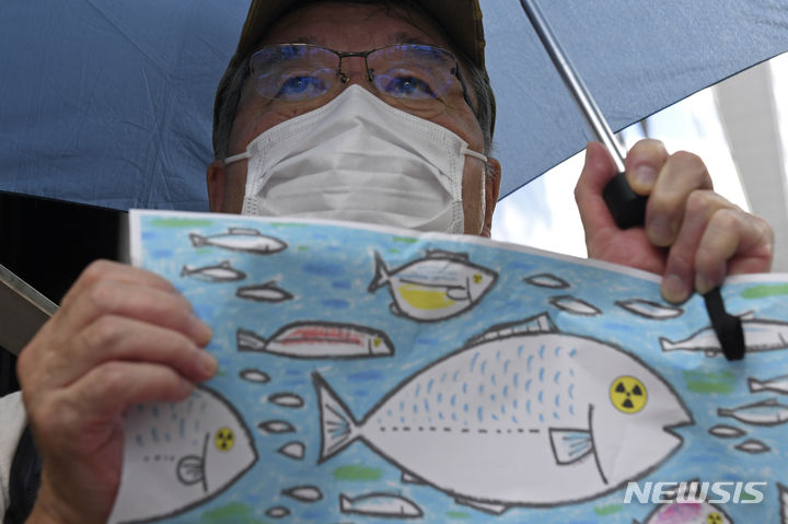 [도쿄=AP/뉴시스] 24일 일본 도쿄의 도쿄전력 본사 앞에서 오염수 해양 방류 반대 시위 참가자가 방사능에 오염된 물고기 그림을 들고 있다. 일본 정부와 도쿄전력은 24일 오후 1시부터 후쿠시마 제1원자력발전소 오염수의 해양 방류를 시작한다. 2023.08.24.