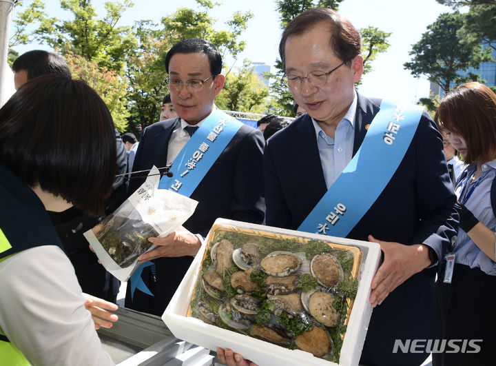 [서울=뉴시스] 추상철 기자 = 노동진(왼쪽) 수협중앙회장과 조승환 해양수산부 장관이 8일 서울 여의도 국회 소통관 앞에서 열린 수산물 소비촉진을 위한 홍보 행사에서 전복을 구매하고 있다. (공동취재사진) 2023.09.08. photo@newsis.com