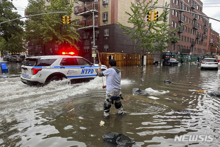 [뉴욕=AP/뉴시스] 29일(현지시각) 미국 뉴욕 브루클린 자치구 침수 도로에서 한 남성이 배수구를 뚫고 있다. 뉴욕 일대에 폭우가 쏟아져 일부 지하철과 통근 열차 운행이 중단돼 출근길 시민들이 대란을 겪었다. 2023.09.30.