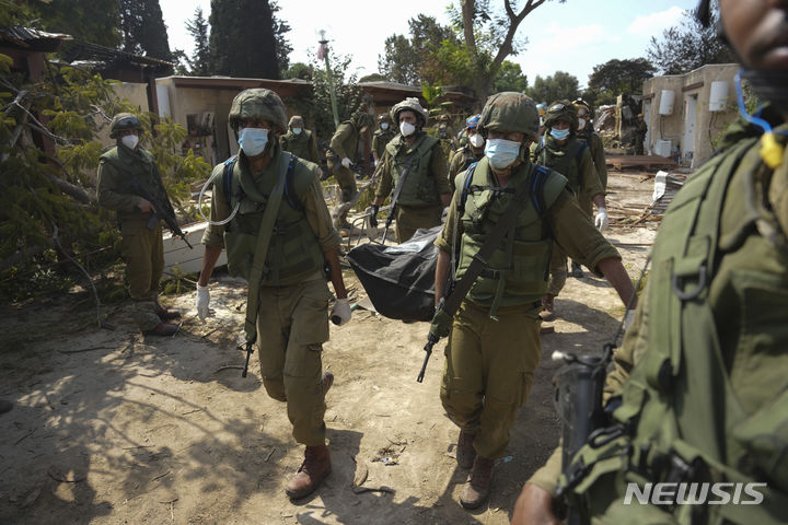 [크파르 아자=AP/뉴시스] 10일(현지시간) 이스라엘 크파르 아자에서 이스라엘 군인들이 팔레스타인 하마스군의 습격으로 숨진 희생자의 시신을 옮기고 있다. 2023.10.11.