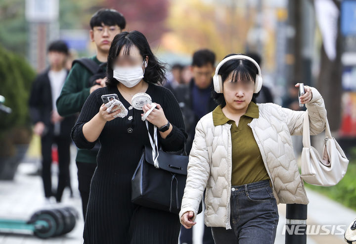 [서울=뉴시스] 정병혁 기자 = 낮 최고기온이 21~28도로 예보된 2일 서울 종로구 세종대로 인근에서 한 시민이 손선풍기를 들고 이동하고 있다. 2023.11.02. jhope@newsis.com