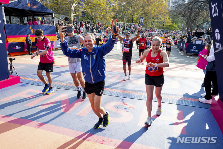 [뉴욕=AP/뉴시스] 5일(현지시간) 미국 뉴욕에서 열린 뉴욕 마라톤 대회에 참가한 러너들이 결승선을 통과하고 있다. 2023.11.06.