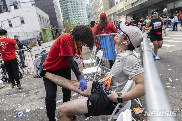 [뉴욕=AP/뉴시스] 5일(현지시간) 미국 뉴욕에서 열린 뉴욕 마라톤 대회에 참가한 러너가 응급처치를 받고 있다. 2023.11.06.