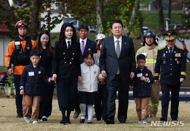 [서울=뉴시스] 전신 기자 = 윤석열 대통령과 부인 <BR>김건희 여사가 9일 서울 용산어린이정원 잔디마당에서 열린 제61주년 소방의 날 기념식에 순직 소방관 자녀의 손을 잡고 입장하고 있다.<BR> 2023.11.09. photo1006@newsis.com