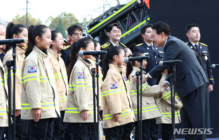 [서울=뉴시스] 전신 기자 = 윤석열 대통령이 9일 서울 용산어린이정원 잔디마당에서 열린 제61주년 소방의 날 기념식을 마친 뒤 공연을 선보인 어린이 합창단을 격려하고 있다.<BR> 2023.11.09. photo1006@newsis.com