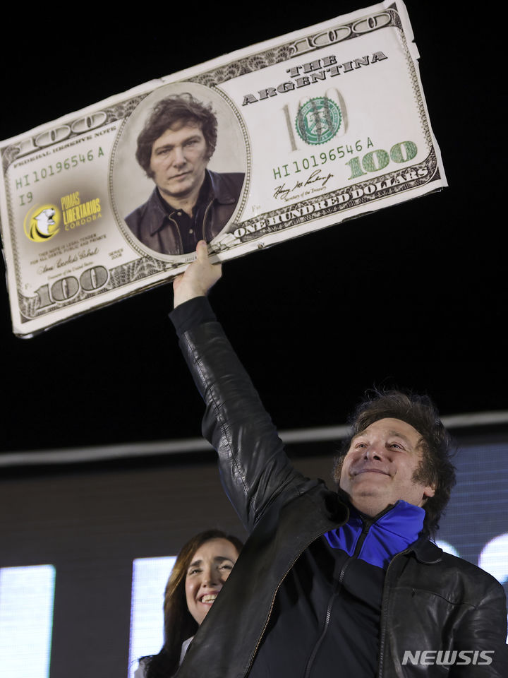 [코르도바=AP/뉴시스] 아르헨티나 차기 대통령으로 당선된 하비에르 밀레이 당선인이 지난 16일(현지시간) 아르헨티나 코르도바 유세 현장에서 자신의 사진이 부착된 100달러권 모형을 들고 있는 모습. 2023.11.21.
