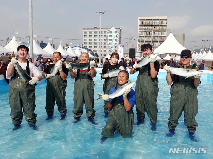 [제주=뉴시스] 지난해 11월23일 제주 서귀포시 모슬포항 일원에서 열린 제23회 최남단 방어축제에서 방어 맨손 잡기 체험에 참여한 시민들이 방어를 들고 있다. 2023.11.23. oyj4343@newsis.com