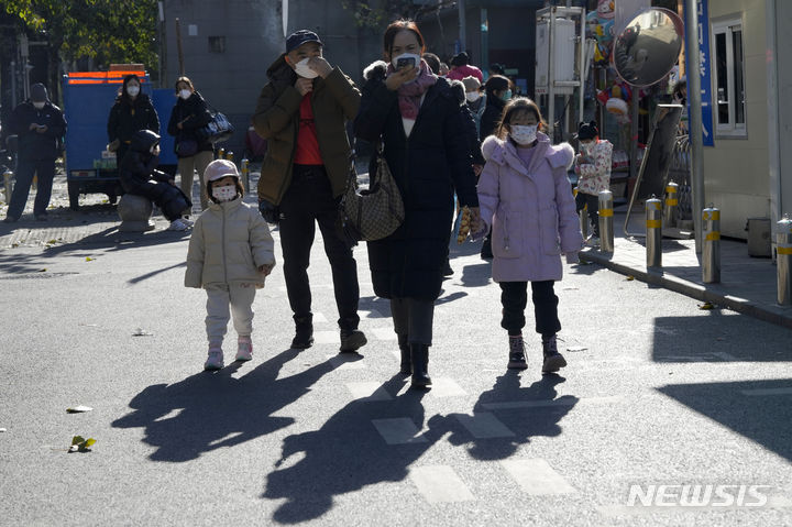 [AP/뉴시스] 중국에 호흡기 질환 발병이 급증한 가운데 24일 베이징에서 한 가족이 마스크를 쓰고 아동병원 옆을 지나가고 있다 