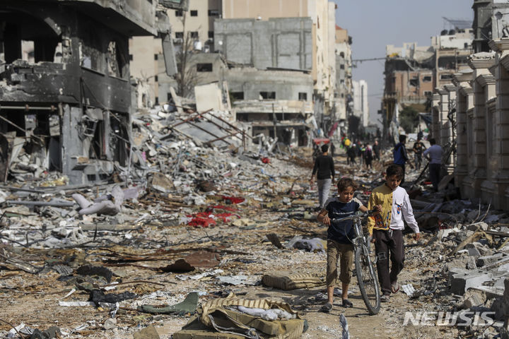 [가자시티=AP/뉴시스] 이스라엘과 하마스의 인도주의 휴전 첫날인 24일(현지시간) 가자지구 최대 도시 가자시티에서 팔레스타인 주민들이 파괴된 거리를 평화롭게 지나고 있다. 2023.11.25.