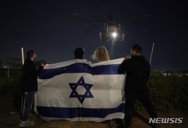 [텔아비브=AP/뉴시스] 28일(현지시각) 이스라엘 텔아비브의 이칠로프 병원에서 이스라엘 국기를 펼쳐 든 사람들이 하마스로부터 풀려난 인질들을 태운 헬기가 착륙하는 것을 지켜보고 있다. 2023.11.30.