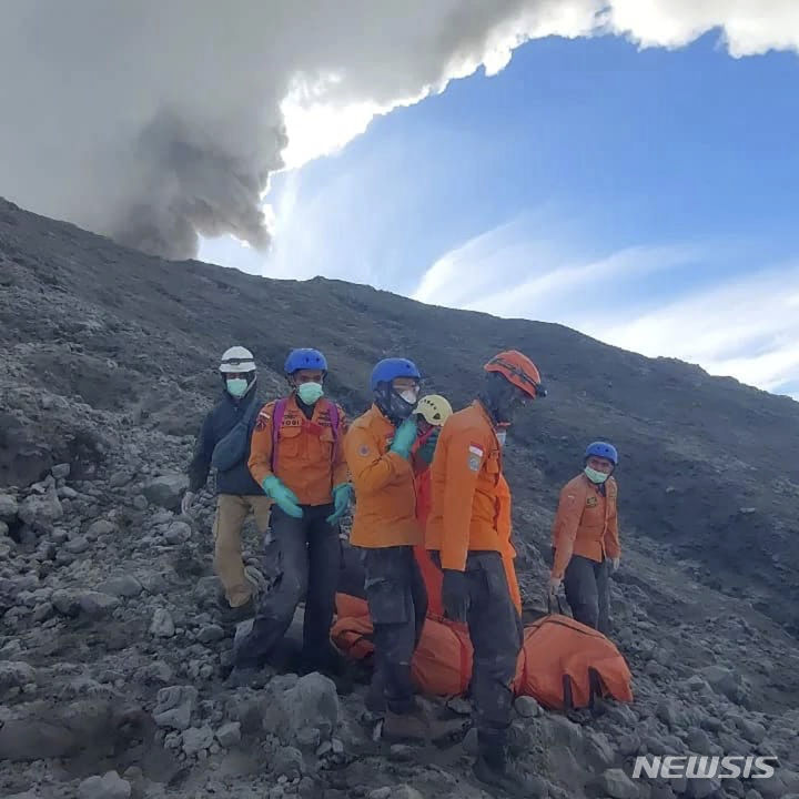 [아감=AP/뉴시스] 5일(현지시각) 인도네시아 국립수색구조국(BASARNAS)이 공개한 사진에 구조대원들이 수마트라섬 아감에서 므라피 화산 폭발로 숨진 한 등산객의 시신을 수습하고 있다. 므라피 화산 경사면을 수색하던 구조대는 이틀 전 화산 폭발로 고립됐다가 숨진 등산객의 시신을 더 찾아내 사망자 숫자는 13명이 됐다. 2023.12.05.
