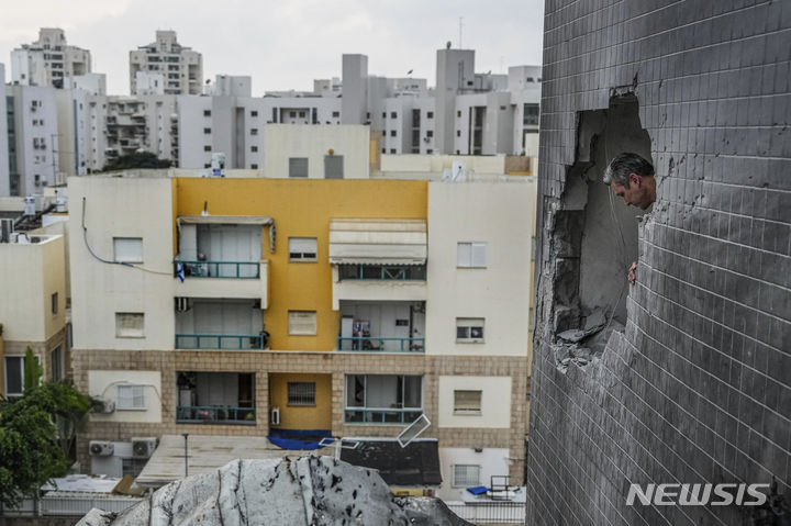 [아슈켈론=AP/뉴시스] 5일(현지시각) 이스라엘 아슈켈론에서 한 남성이 하마스의 로켓 공격으로 건물 벽에 뚫린 구멍을 살피고 있다. 2023.12.06.