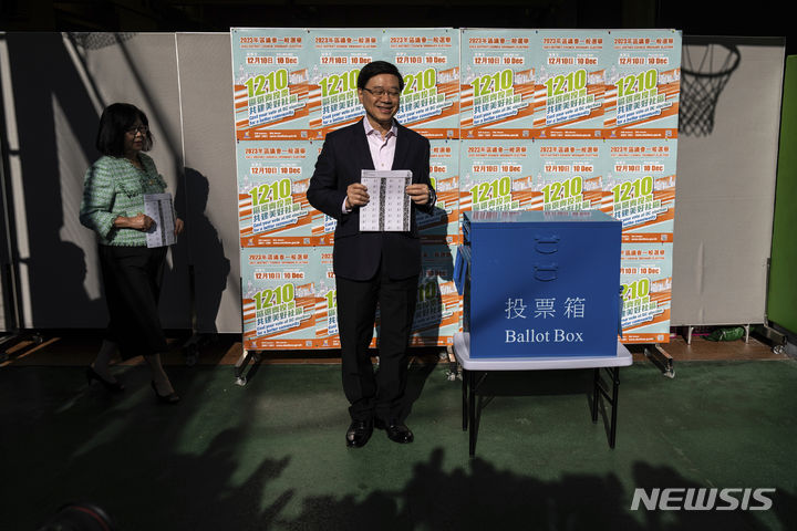[홍콩=AP/뉴시스] 존리 홍콩 행정장관이 10일 홍콩 구의원 선거 투표소에서 배우자 재닛 람과 함께 투표하고 있다. 2023.12.10.