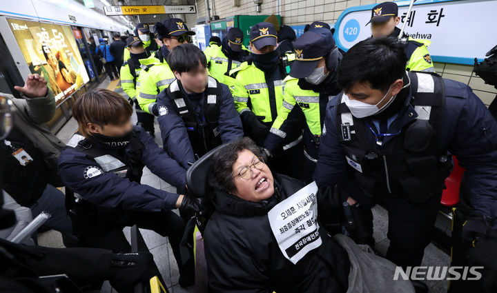 [서울=뉴시스] 김선웅 기자 = 전국장애인차별철폐연대 회원이 26일 서울 지하철4호선 혜화역에서 권리중심공공일자리 최중증장애인 노동자 400명 해고철회를 촉구하는 선전전을 하는 중 퇴거되고 있다. 2023.12.26. mangusta@newsis.com