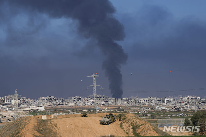 [가자지구=AP/뉴시스] 29일(이스라엘) 이스라엘의 공습으로 가자지구에서 연기가 피어오르는 가운데 이스라엘 군인들이 이스라엘 남부 가자지구 인근에 진을 치고 있다. 2023.12.29.