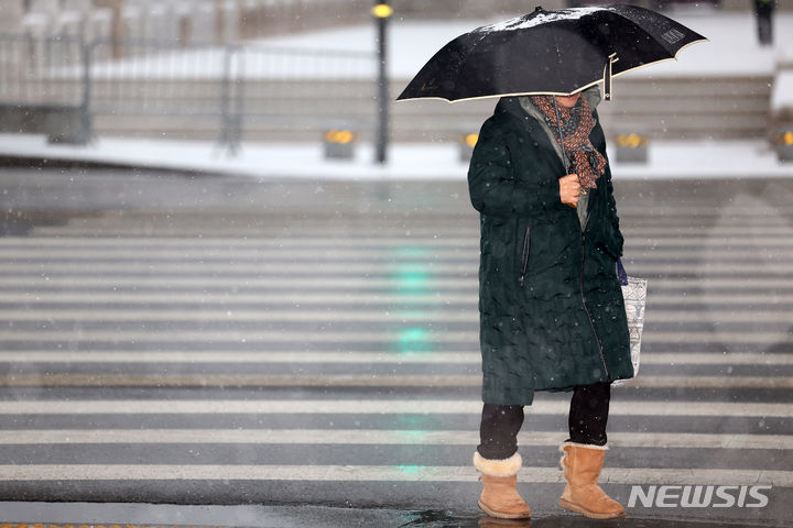 [서울=뉴시스] 김명년 기자 = 수요일인 오는 17일은 전국이 흐리다 오후부턴 대부분 지역에 비 또는 눈이 오겠다. 사진은 눈이 내린 지난 9일 오전 서울 종로구 광화문삼거리에서 한 시민이 우산을 쓰고 이동하는 모습. 2024.01.09. kmn@newsis.com