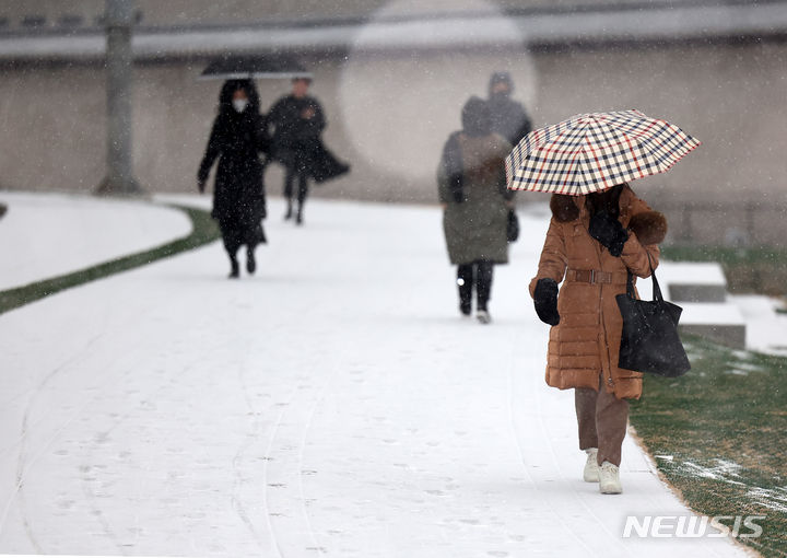 [서울=뉴시스] 김명년 기자 = 눈이 내린 9일 오전 서울 종로구 광화문에서 시민들이 우산을 쓰고 이동하고 있다. 2024.01.09. kmn@newsis.com