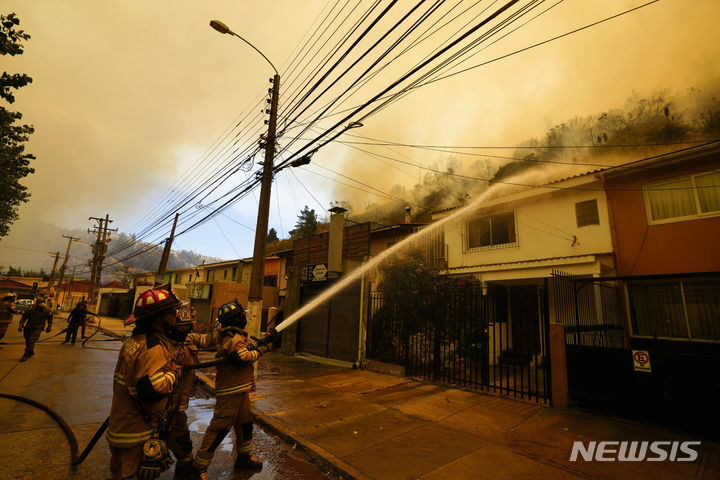 [비냐델마르=AP/뉴시스] 3일(현지시간) 칠레 비냐델마르에서 산불이 번지는 것을 막기 위해 소방관들이 주택 지붕에 물을 뿌리는 모습. 2024.2.4