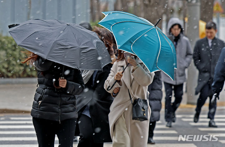 [서울=뉴시스] 김금보 기자 = 오후 한때 진눈깨비와 돌풍이 몰아친 5일 서울 시내 한 거리에서 시민들이 우산을 쓰고 이동하고 있다. 2024.02.05. kgb@newsis.com