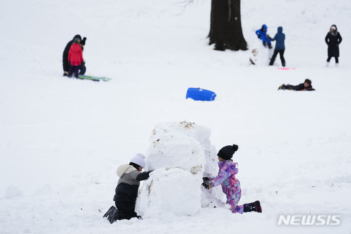 [펜실베니아=AP/뉴시스] 많은 눈이 내린 13일(현지시간) 미국 펜실베니아주 도일스타운에서 어린이들이 눈사람을 만들고 있다. 2024.02.14.