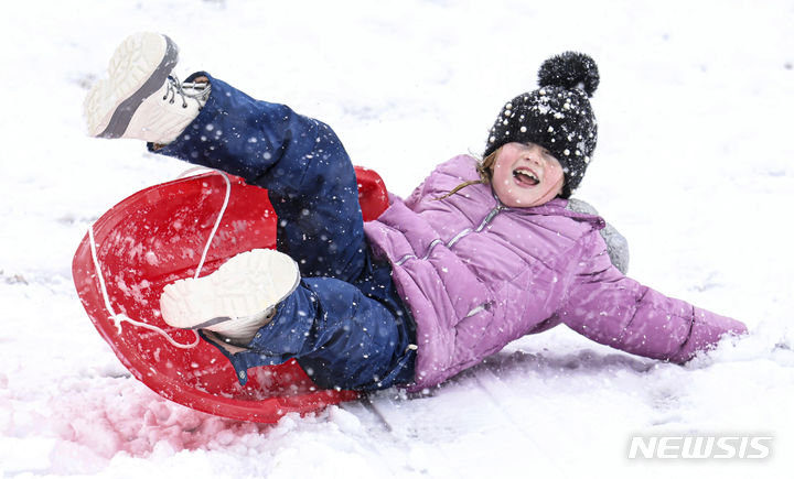 [매사추세츠=AP/뉴시스] 많은 눈이 내린 13일(현지시간) 미국 매사추세츠주에서 한 어린이가 썰매를 타고 있다. 2024.02.14.