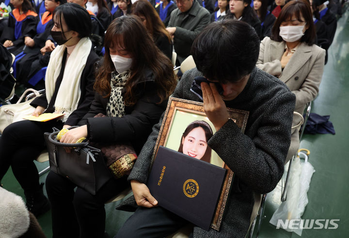 [서울=뉴시스] 김선웅 기자 = 15일 서울 구로구 성공회대학교에서 열린 학위수여식에서 이태원 참사로 유명을 달리한 故 진세은 학생의 유족이 명예학위증을 들고 눈물을 닦고 있다. 2024.02.15. mangusta@newsis.com