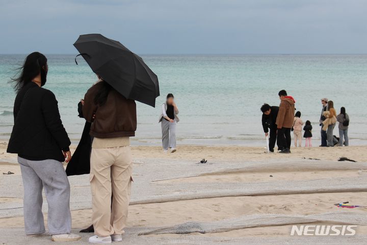 [제주=뉴시스] 양영전 기자 = 오후 제주시 조천읍 함덕해수욕장을 찾은 관광객들이 우산을 쓴 채 바다를 보며 즐거운 시간을 보내고 있다. 2024.02.18. 0jeoni@newsis.com 