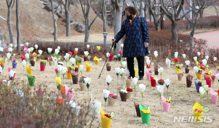 [대구=뉴시스] 이무열 기자 = 18일 대구 동구 시민안전테마파크에서 열린 2·18 대구지하철 화재 참사 21주기 추모식을 찾은 한 시민이 추모 꽃을 바라보고 있다. 2024.02.18. lmy@newsis.com