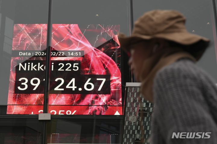 [도쿄=AP/뉴시스]한 사람이 22일 일본 도쿄의 한 증권회사에서 닛케이225지수를 표시하는 주식 시황판 앞을 걷고 있다. 2024.02.22.
